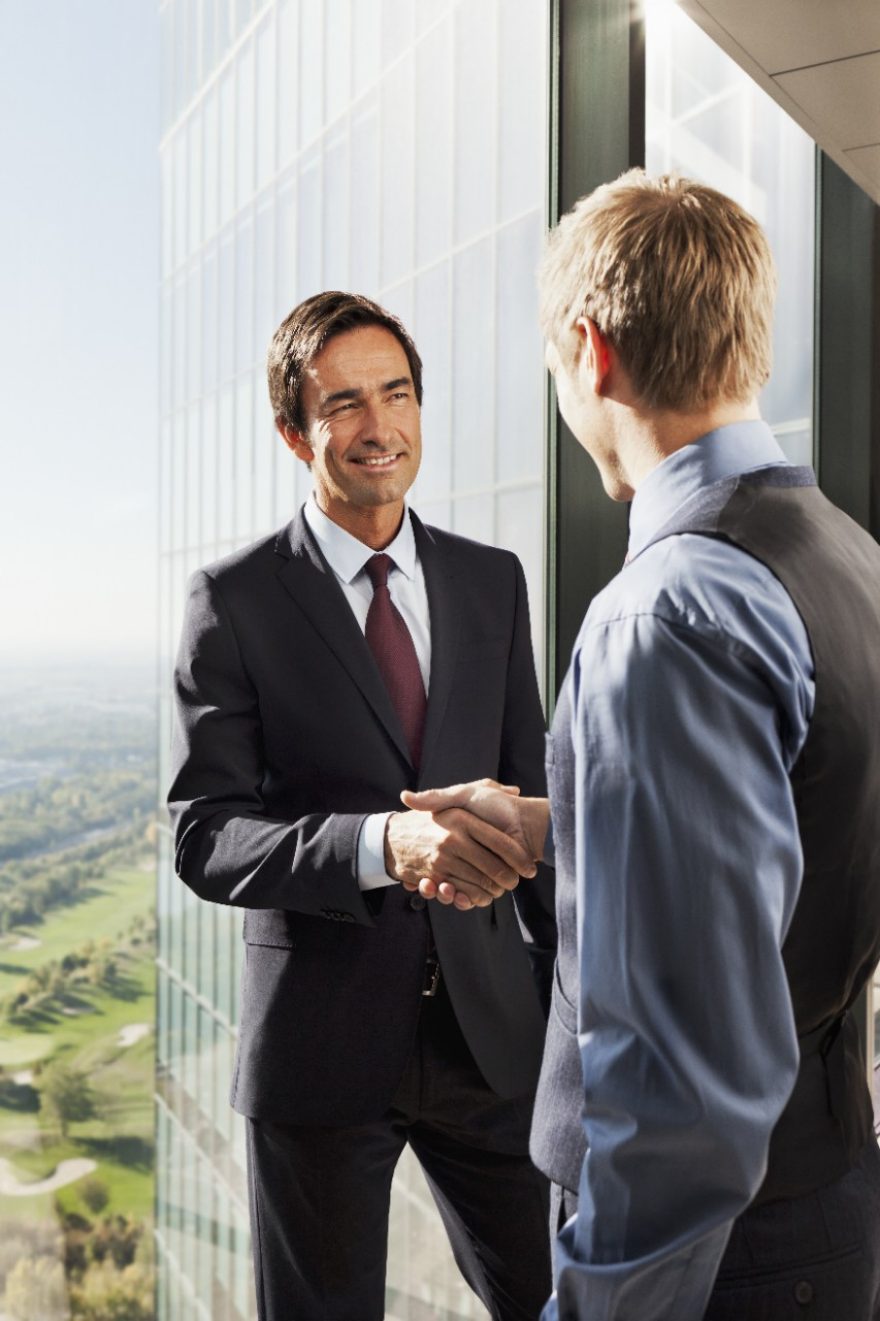 Business men shaking hands in high rise building with a stunning view
